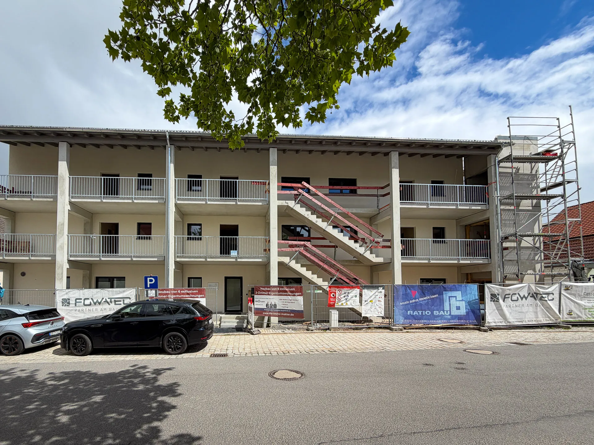 Neubau Trunstadt — Straßenansicht mit Laubengang-Balkonen, aktueller Bautenstand